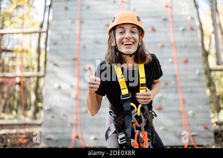 Portrait d'une jeune femme bien équipée debout devant du mur d'escalade au parc d'attractions Banque D'Images