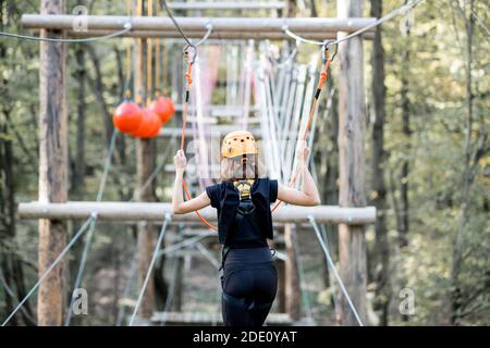 Jeune femme bien équipée ayant une activité de loisirs, des cordes d'escalade dans le parc avec des obstacles à l'extérieur Banque D'Images