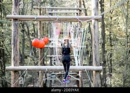 Jeune femme bien équipée ayant une activité de loisirs, des cordes d'escalade dans le parc avec des obstacles à l'extérieur Banque D'Images