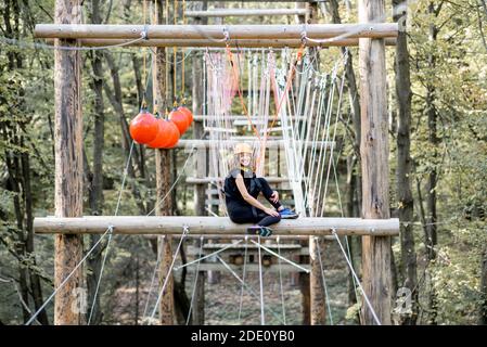 Jeune femme bien équipée ayant une activité de loisirs, des cordes d'escalade dans le parc avec des obstacles à l'extérieur Banque D'Images