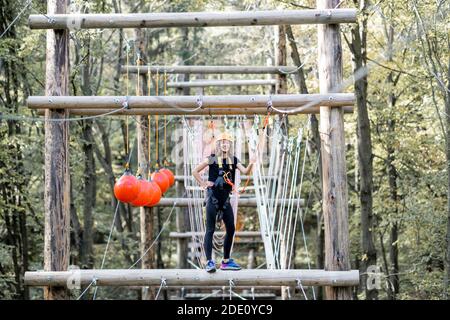 Jeune femme bien équipée ayant une activité de loisirs, des cordes d'escalade dans le parc avec des obstacles à l'extérieur Banque D'Images