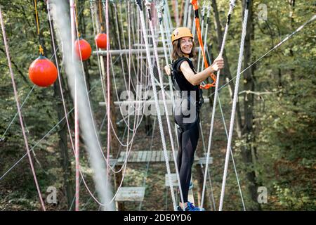 Jeune femme bien équipée ayant une activité de loisirs, des cordes d'escalade dans le parc avec des obstacles à l'extérieur Banque D'Images