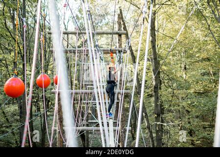 Jeune femme bien équipée ayant une activité de loisirs, des cordes d'escalade dans le parc avec des obstacles à l'extérieur Banque D'Images