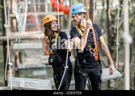 Portrait d'un homme et d'une femme bien équipés ayant une activité de loisirs, des cordes d'escalade dans le parc avec des obstacles à l'extérieur Banque D'Images