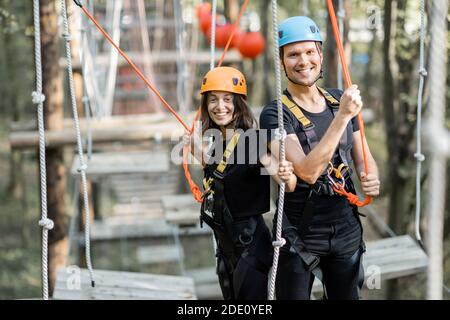 Portrait d'un homme et d'une femme bien équipés ayant une activité de loisirs, des cordes d'escalade dans le parc avec des obstacles à l'extérieur Banque D'Images