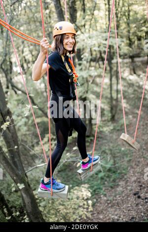 Jeune femme bien équipée ayant une activité de loisirs, des cordes d'escalade dans le parc avec des obstacles à l'extérieur Banque D'Images