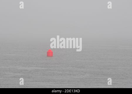 Une petite bouée de navigation rouge dans un océan brumeux. Il s'agit d'une bouée rouge. L'océan est calme et très brumeux. Banque D'Images