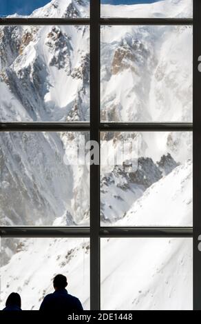 Silhouette de deux personnes regardant le paysage majestueux de montagne à travers Une immense fenêtre dans les Alpes Banque D'Images