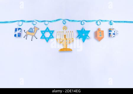 Hanoukkah, ou Chanukah, festival de fond clair avec une série de symboles juifs accrochés d'un ruban bleu: Don, dreidel, star de David, menorah. F Banque D'Images