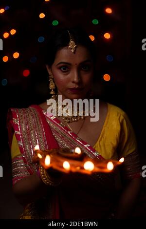 Portrait d'une femme bengali indienne magnifique brunette devant le fond bokeh lumineux coloré dans la soirée de Diwali. Style de vie indien Banque D'Images