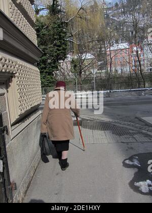 Une vieille femme avec un bâton de marche marche marche dans les rues Banque D'Images