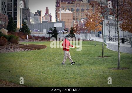 Homme isolé pratiquant des arts martiaux avec un bâton dans Lower Manhattan dans un parc dans le quartier financier. New York, États-Unis Banque D'Images