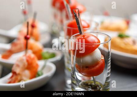 Tomates cerises et canapés mozzarella sur brochettes dans un verre verre avec un fond de crevettes royales en gros plan Banque D'Images