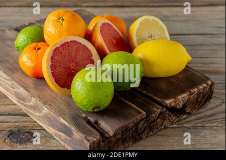 Moitiés d'agrumes frais sur fond en bois. Orange, pamplemousse, lime, citron, rondelles coupées à la mandarine Banque D'Images