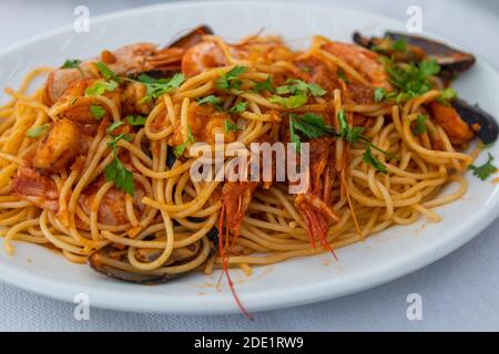 Spaghetti colorés aux fruits de mer. Plat méditerranéen traditionnel, Taverne sur la plage de Manganari, île d'iOS, Grèce. Banque D'Images