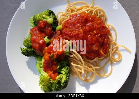 Plat végétalien composé de spaghetti aux grains entiers, de brocoli et de sauce tomate fraîche Banque D'Images