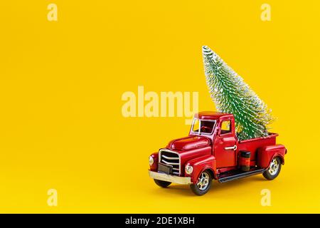 Camion de jouet rétro rouge avec arbre de Noël sur la caisse de camion sur fond jaune. Livraison, noël, concept du nouvel an. Voiture modèle vintage avec Christma Banque D'Images