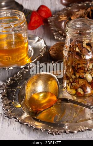 Cuisiner un délicieux dessert - noix au miel. Un pot rempli de noix se tient sur une plaque métallique Banque D'Images