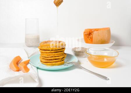 Une pile de crêpes de citrouille d'automne avec des graines de Chia et du miel sur un fond clair. Délicieux régime végétarien sain petit déjeuner. Le concept de prendre Banque D'Images