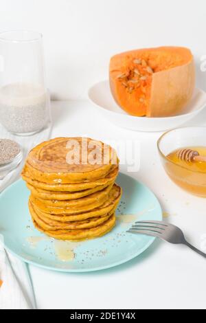 Une pile de crêpes de citrouille d'automne avec des graines de Chia et du miel sur un fond clair. Délicieux régime végétarien sain petit déjeuner. Le concept de prendre Banque D'Images