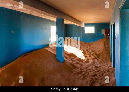 Intérieur de maison négligé avec des murs bleus enterrés dans le sable dans le village fantôme d'Al Madame dans les Émirats arabes Unis. Banque D'Images