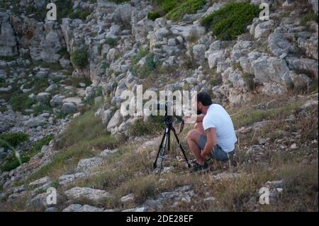 Photographe prenant des photos au coucher du soleil sur la côte rocheuse Banque D'Images