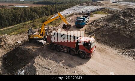 Vue de dessus des travaux de construction. Terrassement à l'exploitation minière à ciel ouvert. Extraction minérale. La pelle hydraulique charge le sol dans le tombereau. Banque D'Images