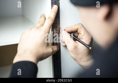 Mains de menuisier prenant la mesure avec crayon de planche en bois. Concept de bricolage et de fabrication de meubles Banque D'Images