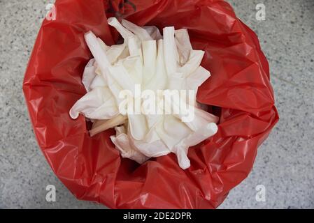 Vue de dessus des gants chirurgicaux usagés dans une poubelle rouge bac pour l'élimination des déchets biologiques dangereux Banque D'Images