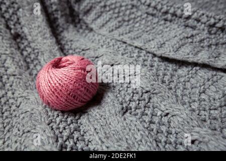 boule de laine rose sur un pull gris tricoté Banque D'Images