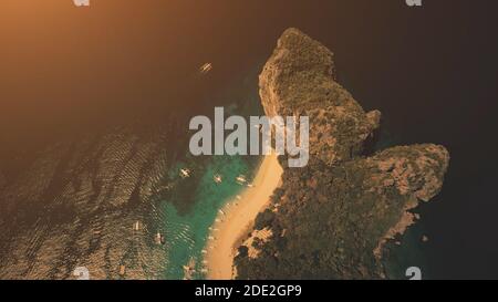 Coucher de soleil en haut de l'île tropicale vallonnée sur l'océan golfe en vue aérienne. Le soleil se couche à la lumière de la forêt tropicale sur l'île de Palawan, aux Philippines. Paysage marin bleu foncé spectaculaire sur un tir de drone à lumière douce Banque D'Images