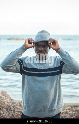 Afro homme mettant un chapeau d'hiver. Banque D'Images