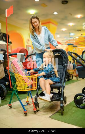 Mère et fille dans poussette de bébé, magasin de jouets Banque D'Images