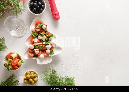 Salade Caprese des fêtes en forme d'arbre de Noël, vin pétillant et en-cas différents pour les fêtes de Noël. Vue de dessus. Banque D'Images