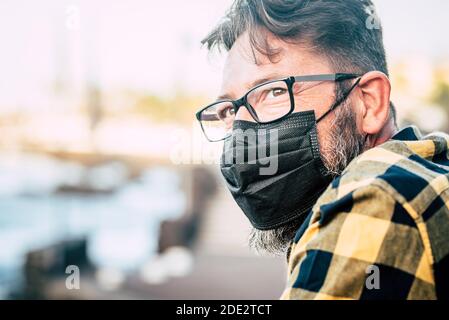 Gros plan portrait d'un beau homme avec un masque médical et des gloses pour protéger contre l'urgence pandémique covid-19 du coronavirus - personnes et mesures de sécurité Banque D'Images