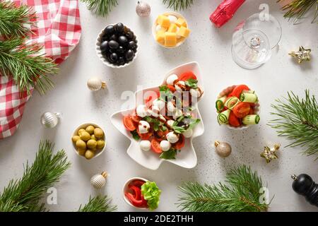 Dîner de Noël avec salade Caprese et divers plats de légumes pour les fêtes de Noël sur table blanche. Vue de dessus. Banque D'Images