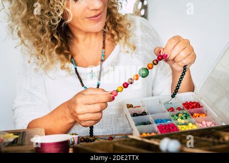 Portrait d'une femme adulte créant des bracelets de perles et collier à c'est la maison pour les affaires modernes et à la mode - les gens ont passé le temps à la maison faisant des passe-temps ou al Banque D'Images