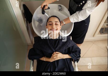 Le coiffeur lave les cheveux de la femme, vue du dessus Banque D'Images