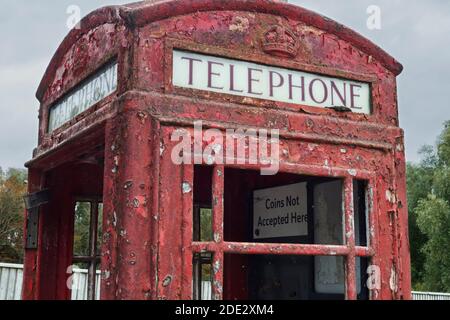Ancienne boîte téléphonique rouge abandonnée avec verre cassé et cassé peinture rouge écaillée Banque D'Images