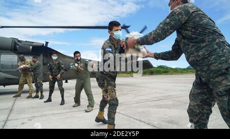 Des soldats et des aviateurs américains et honduriens chargent l'aide humanitaire sur un HÉLICOPTÈRE UH-60 Black Hawk pour aider les familles bloquées par l'ouragan Iota le 27 novembre 2020 à la base aérienne de Soto Cano, au Honduras. L'ouragan Iota a balayé l'Amérique centrale en détruisant de grandes parties de la côte et en inondant les routes. Banque D'Images