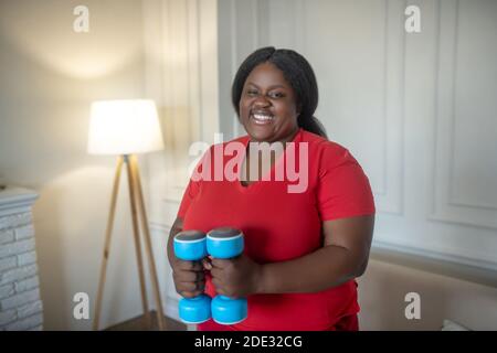 Plus de taille femme afro-américaine ayant un entraînement avec des haltères Banque D'Images