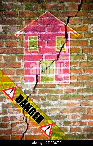 Vieux mur de briques fissuré et vieux avec une maison colorée dessinée dessus - image de concept avec texte de danger écrit dessus. Banque D'Images