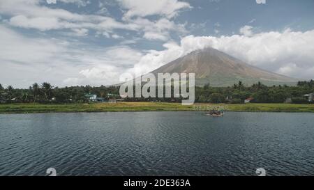 Volcan tropique à l'antenne de la côte du lac. Croisière touristique en bateau dans la vallée de l'herbe verte à terre. Chalets de campagne aux palmiers. Personne de paysage de la nature des Philippines Mont Mayon à la ville de Legazpi Banque D'Images