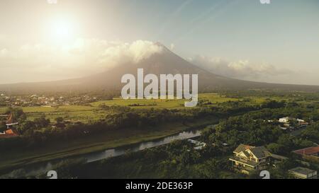 Le soleil brille au-dessus de l'éruption du volcan Mayon. Rivière à flanc de coteau d'herbe verte. Forêt tropicale à l'attraction Legazpi. Philippines campagne à personne paysage de la nature. Prise de vue en lumière douce de qualité cinématographique Banque D'Images