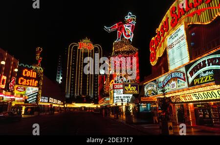 Les néons et autres lumières colorées ont fait ressortir ces panneaux extérieurs pour les casinos et les hôtels la nuit et pendant la journée le long de Fremont Street, le centre-ville original pour les jeux et les bons moments à Las Vegas, Nevada, Etats-Unis. Facilement reconnu dans l'affichage au néon est une cowgirl surnommée Vegas Vickie. Depuis que cette photographie historique a été prise en 1983, Fremont St. a été couvert d'une voûte qui est le plus long écran vidéo au monde et présente un spectacle son et lumière en hauteur aux visiteurs dans la rue piétonne en dessous. Les lumières lumineuses des enseignes au néon sont apparues pour la première fois à Las Vegas en 1929.