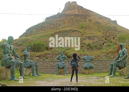 Femme voyageur regardant la forteresse de Gori depuis le Foothill entouré par le Mémorial des sculptures des héros guerriers géorgiens, ville de Gori, Geor Banque D'Images