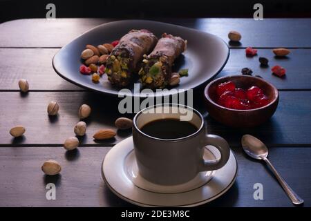 Un café avec un peu de cerise et de cannoli avec des pistaches et des amandes. Petit déjeuner italien. Banque D'Images