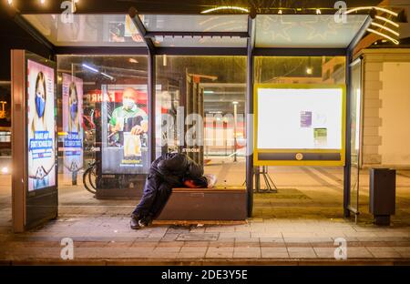 26 novembre 2020, Hessen, Francfort-sur-le-main : un homme sans domicile dormant dans un arrêt de bus. Le bus réfrigéré de la Frankfurt Verein für soziale Heimstätten (Association pour les foyers sociaux) est sur la route pour les sans-abri dans la région de la ville pendant la saison froide entre 9:30 pm et 5:00 am. Il offre le transport vers un abri de nuit, des couvertures, des sacs de couchage et du thé chaud. Photo: Andreas Arnold/dpa Banque D'Images