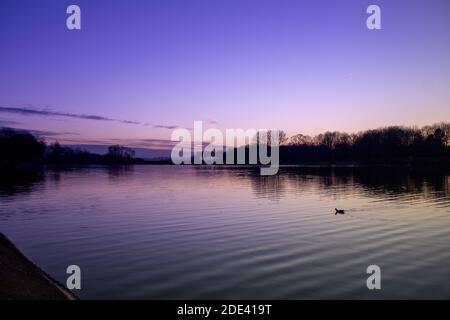 Vue pourpre au coucher du soleil avec ciel pittoresque, nuages à l'horizon réfléchis sur un lac en automne froid, froid et couleur de ver se mélangeant au crépuscule Banque D'Images