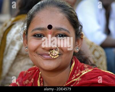 Jeune belle femme positive indienne Gujarati avec de grands bijoux de nez d'or (anneau de nez) et de grands bindi sur le front sourit à la caméra. Banque D'Images